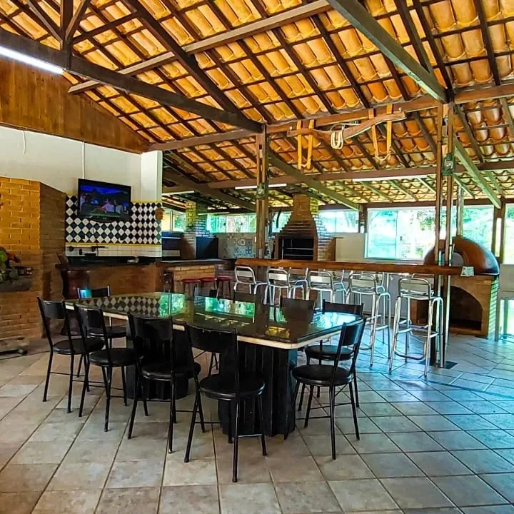 Área gourmet com mesas e televisão
