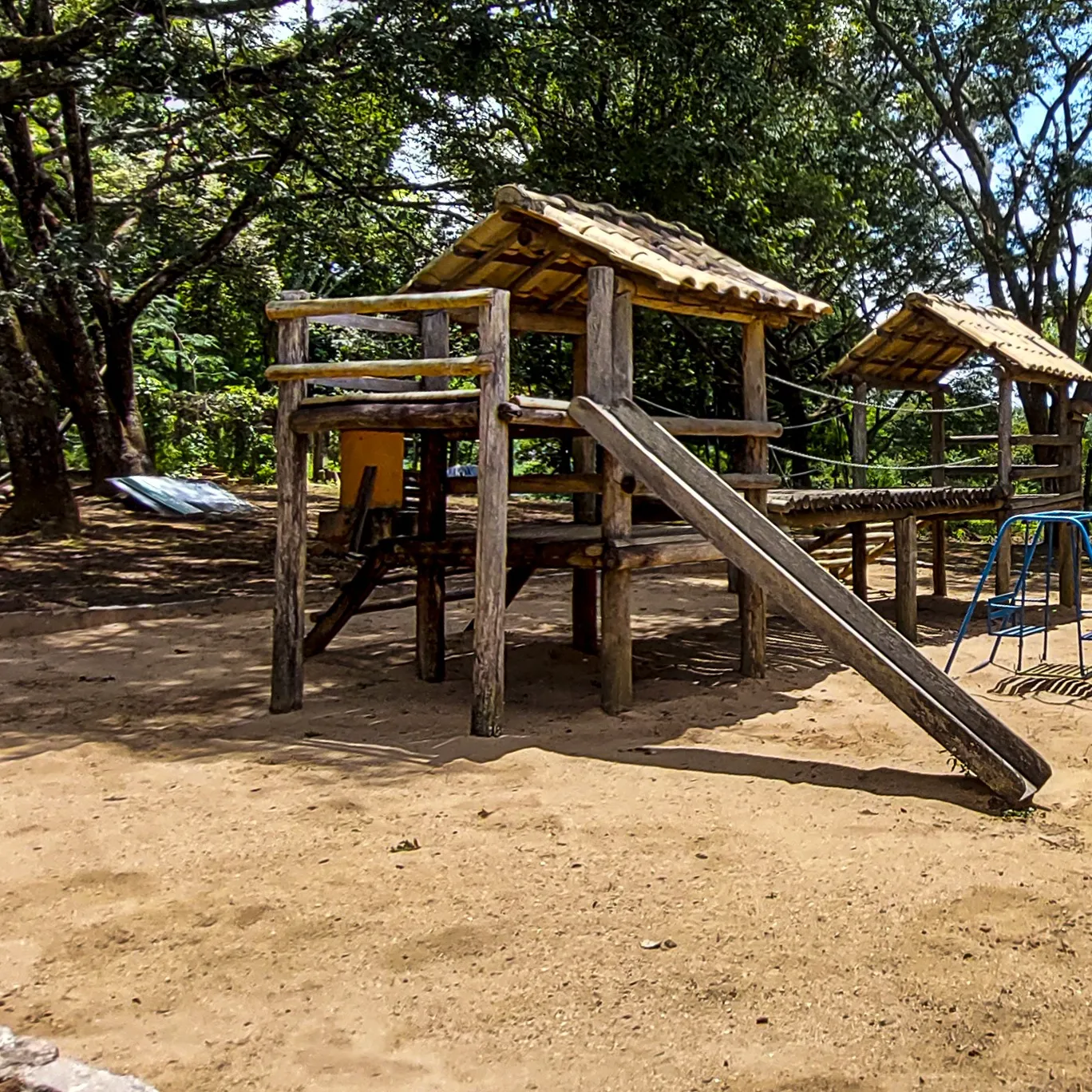 Parquinho infantil de madeira à sombra das árvores