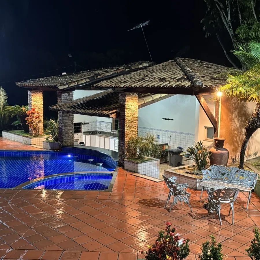 Piscina à noite, com mesa de ferro na borda