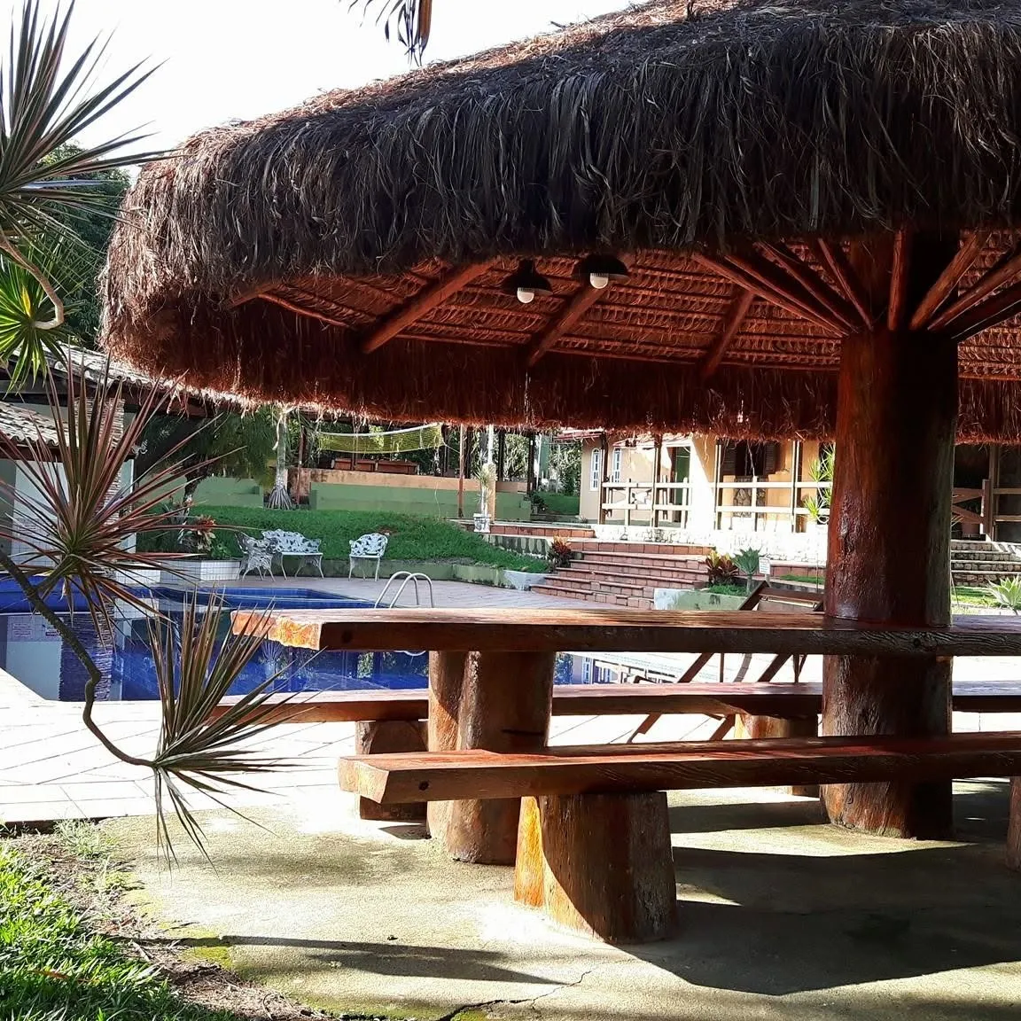 Quiosque de piaçava com mesa longa de madeira