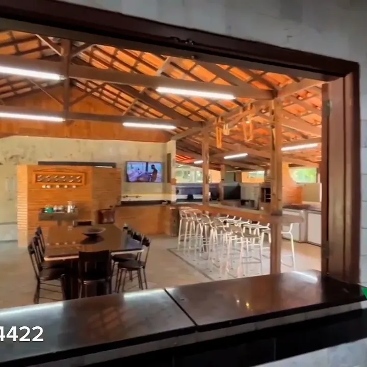 Bar do salão de festas com TV, mesas e cadeiras de madeira
