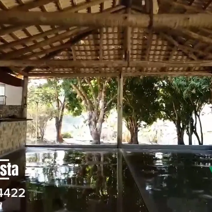 Salão de festas coberto, com vista para as árvores e reflexo da piscina