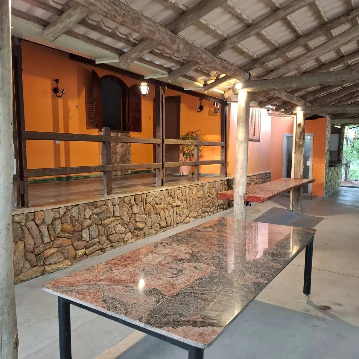 Mesa de granito no salão de festas coberto, com iluminação acesa
